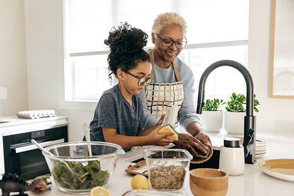 Grandmother and granddaughter washing dishes at the kitchen sink